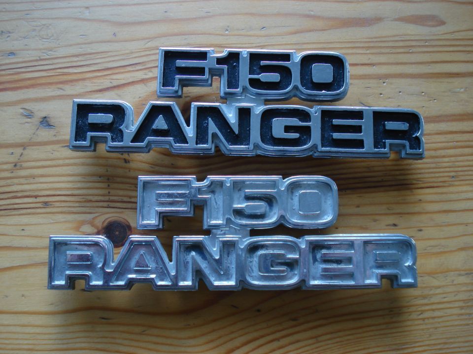 Two sets of Ford F-150 Ranger emblems on a wooden surface