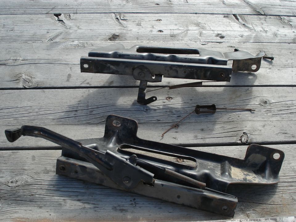 Black car jack and mounting bracket on wooden planks