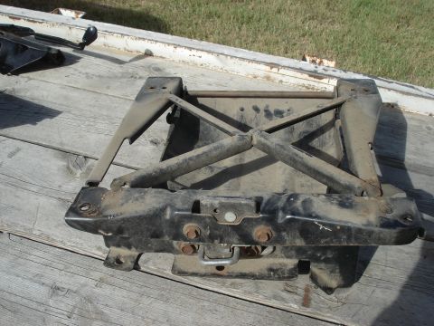 1979 Ford Bronco - A worn black metal seat base is shown from a side angle on a wooden platform.