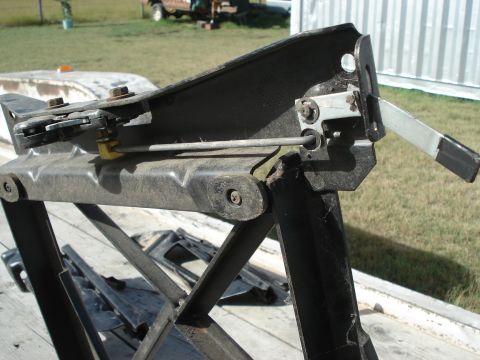 1979 Ford Bronco - Close-up of a vehicle seat adjustment mechanism, showing the lever and rod components.