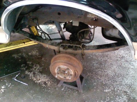 1990 Ford Bronco - The rear suspension and axle are exposed, with tools nearby for maintenance.