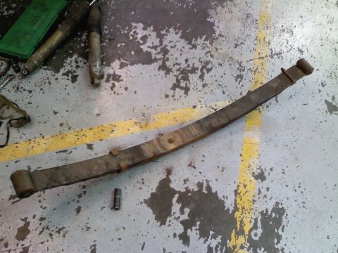 1990 Ford Bronco - A leaf spring and two shock absorbers are visible on a workshop floor.