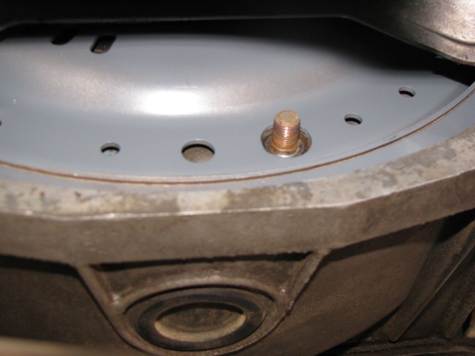 Close-up of gray painted stamped steel pan flange and stud on cast housing