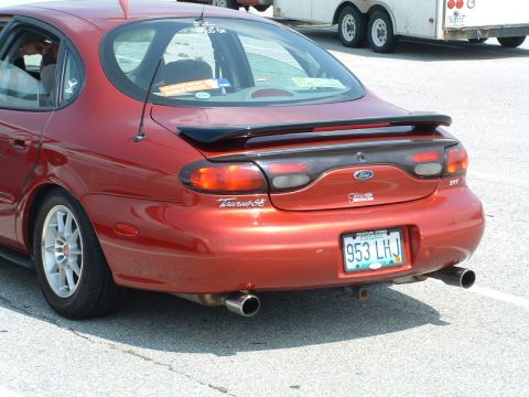 1993 Ford Taurus - Rear view of a red 1993 Ford Taurus SE, a spoiler and aftermarket wheels.