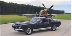1968 Shelby GT500 - A 1968 Shelby GT500 is parked next to a P-51 Mustang airplane on an airfield.