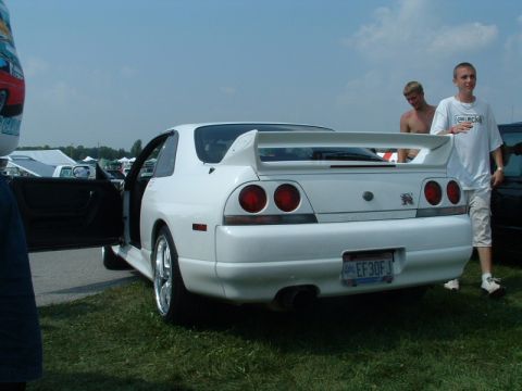 1993 Ford Taurus - A white coupe with a prominent rear spoiler and distinctive round taillights is parked on grass.