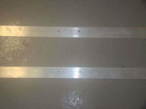 2008 Ford F-250 - Two parallel metal strips are mounted on a gray wall, showing evidence of fasteners.