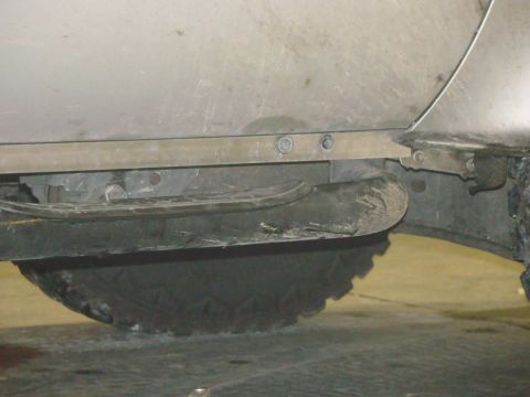 2008 Ford F-250 - A close-up view of a truck's undercarriage reveals a section of the body panel, trim, and a tire.