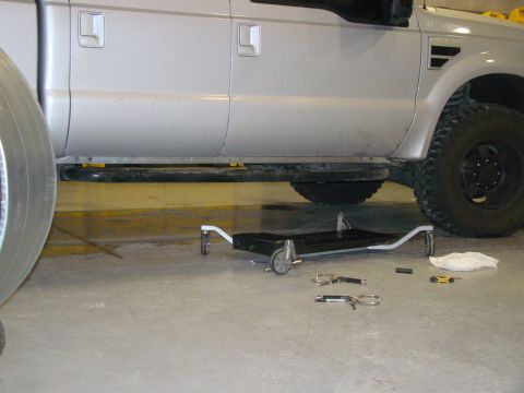 2008 Ford F-250 - Side view of a silver 2008 Ford F-250 truck with a creeper and tools on the floor.
