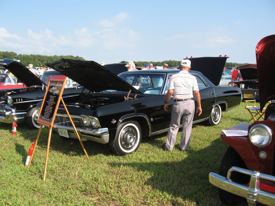 Black 1965 Chevrolet Impala sedan with hood open, viewed from the front-right