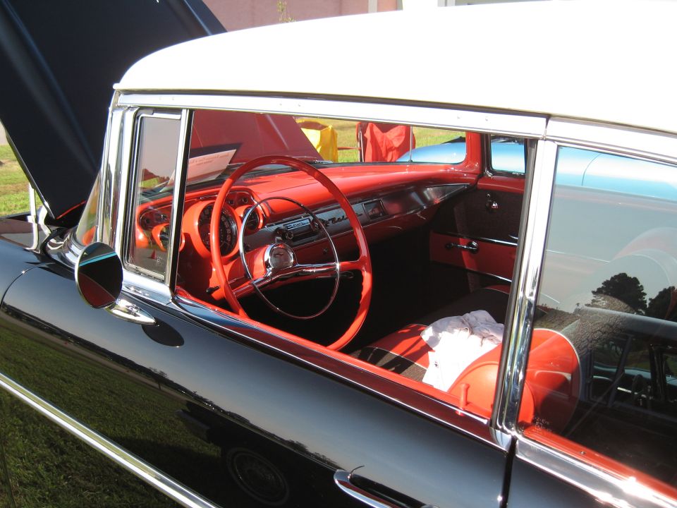 Black 1957 Chevrolet interior with red dashboard and seats, white steering wheel