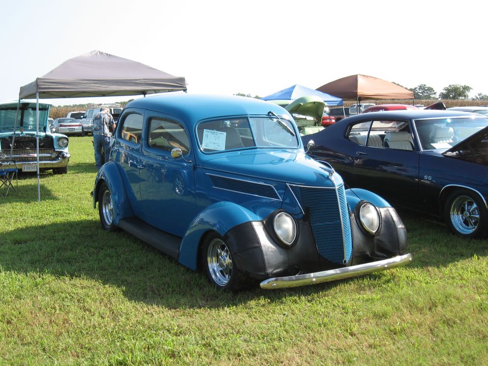 Blue 1937 Ford sedan with black fenders and chrome bumper parked on grass
