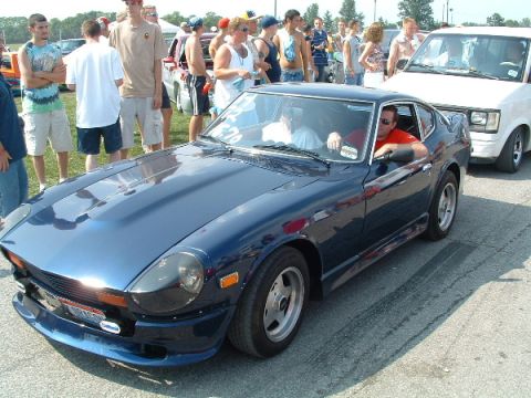 1993 Ford Taurus - A blue Datsun 280Z is parked on asphalt with spectators in the background.