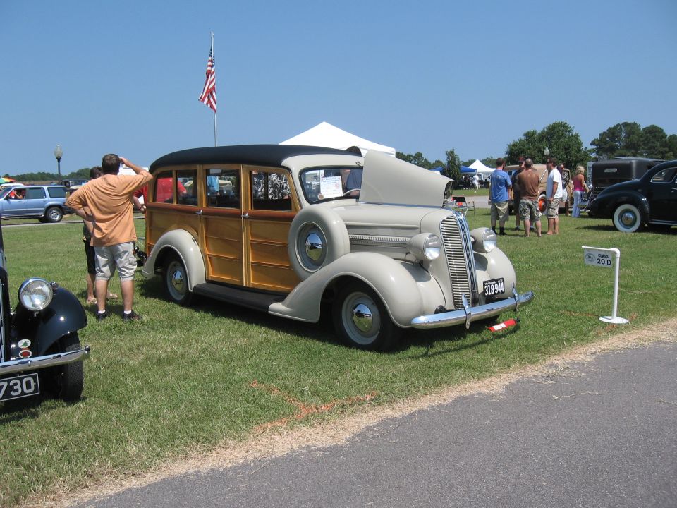 Tan woody wagon with hood up and spare tire on the side