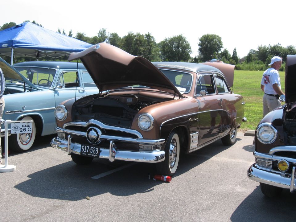 Brown 1950 Ford Custom sedan with hood open, parked next to a blue car