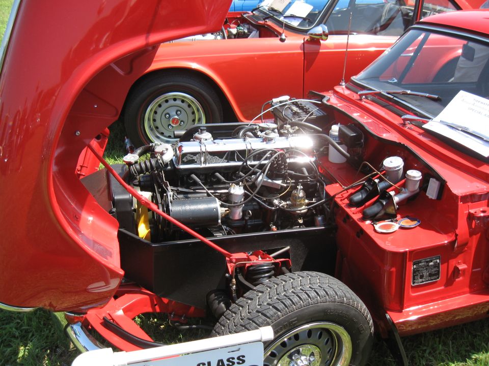 Red sports car with hood open showing engine. Another red car is behind it