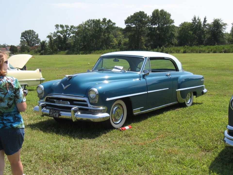 Teal 1950 Chrysler New Yorker with a white roof parked on grass, another car visible behind it
