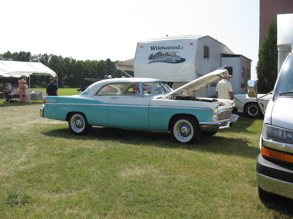 Turquoise and white 1955 coupe with hood open, parked on grass