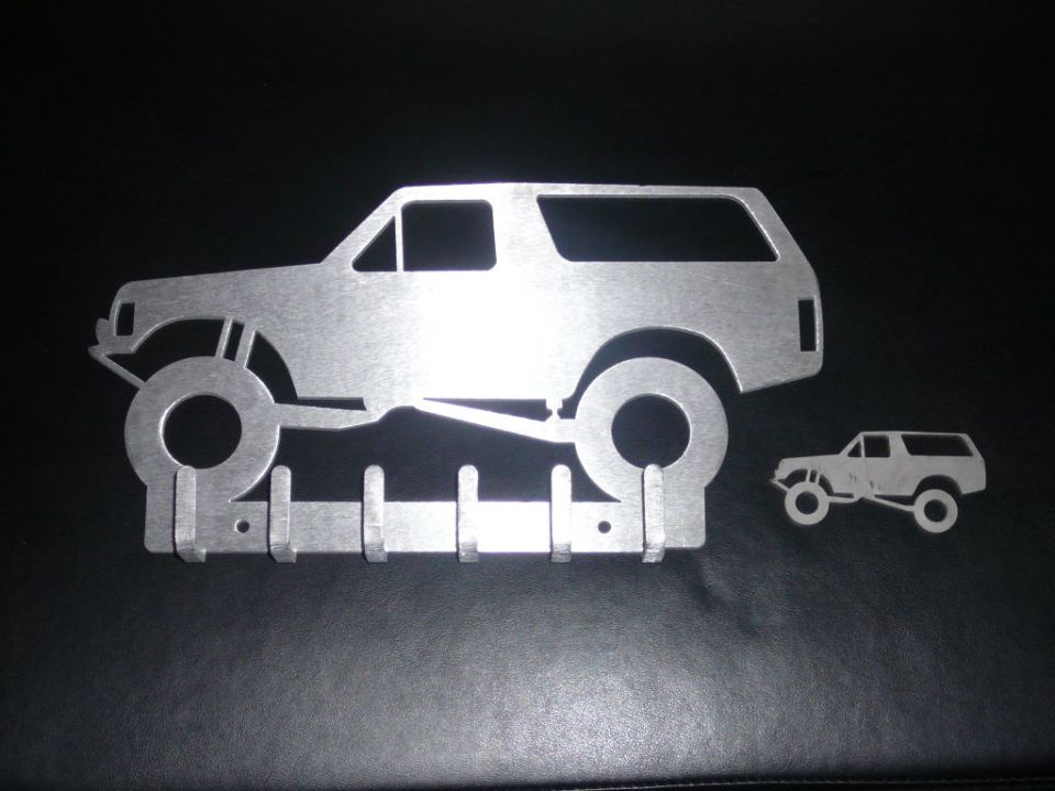 metal wall art shaped like a lifted SUV, with a smaller SUV cutout nearby