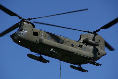 1990 Chevrolet Suburban - A military helicopter is captured mid-flight, its rotors blurred with motion.