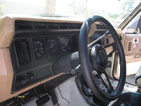 1986 Ford Bronco - The interior of a truck is shown, focusing on the dashboard and steering wheel area. The dashboard has several gauges and air vents.