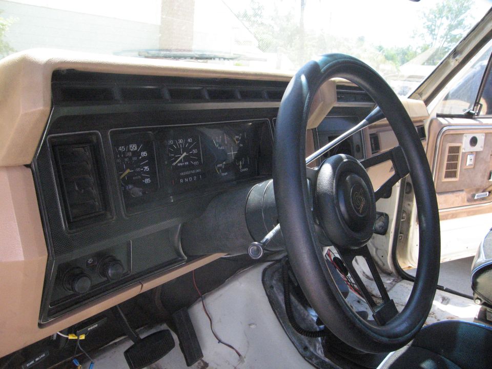 Dashboard and steering wheel of a truck, showing gauges and vents. Some wiring is visible below the dash
