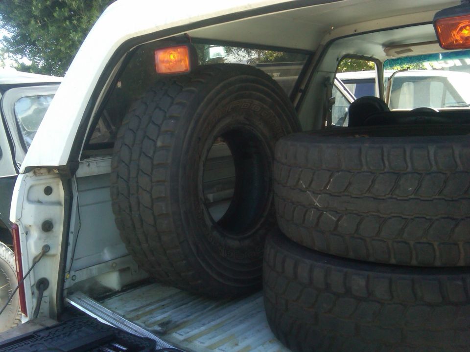 Spare tires stacked in truck bed, one large tire prominent