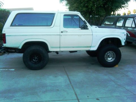 1986 Ford Bronco - Side view of a white 1986 Ford Bronco modified with off-road tires and suspension.