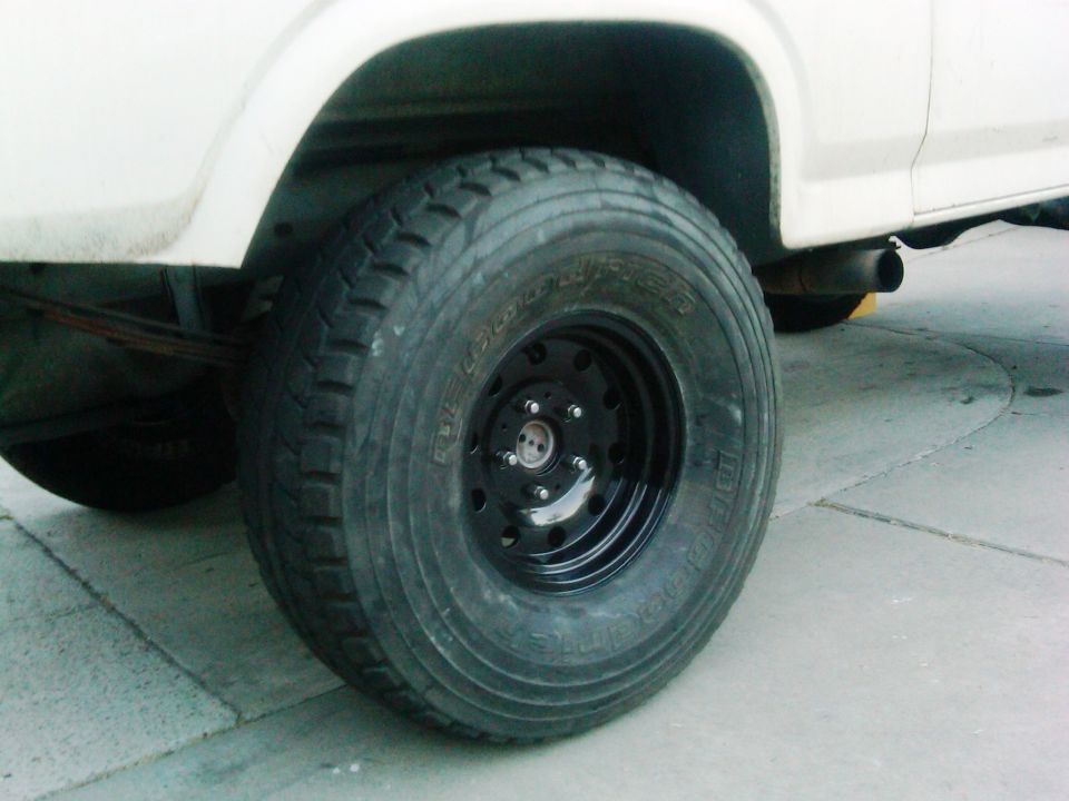 Close-up of a large off-road tire on a white vehicle, showing the exhaust pipe