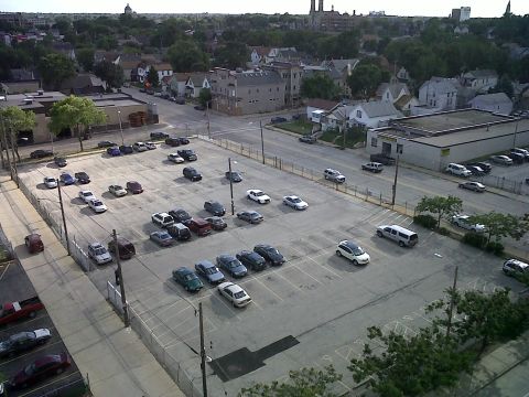2003 Ford Crown Victoria - A wide shot captures a full parking lot under a cloudy sky, with a mix of vehicles and surrounding urban structures.