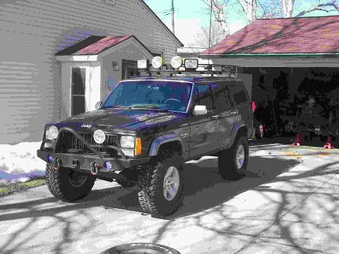 1988 Ford Bronco - Modified Jeep Cherokee XJ parked in a driveway with a garage in the background.