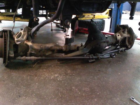1990 Ford Bronco - Front axle assembly removed from a vehicle, showing suspension and steering components.