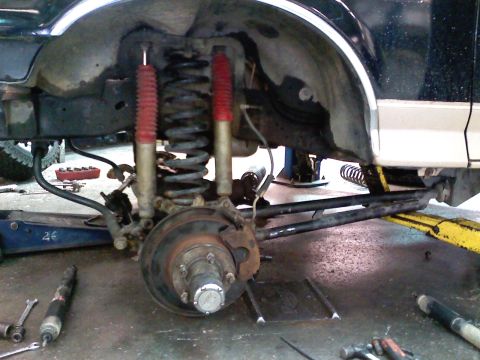 1990 Ford Bronco - Front suspension of a 1990 Ford Bronco undergoing modifications, red shocks and coil springs.
