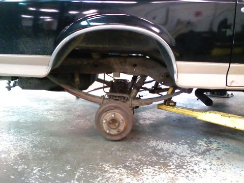 1990 Ford Bronco - The rear axle and suspension components of a truck are visible, with the wheel removed for service.