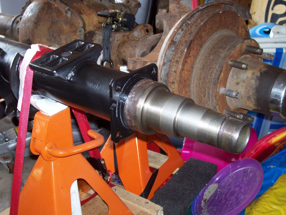 Black painted axle spindle with threaded end, supported by orange jack stands