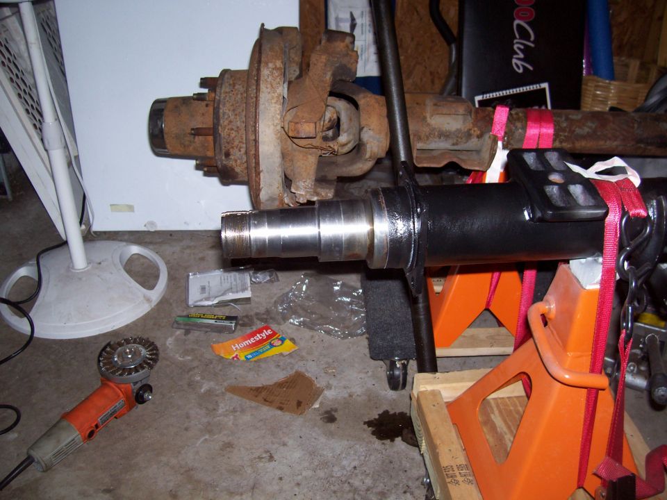 Ford Bronco front axle assembly on jack stands with an angle grinder nearby