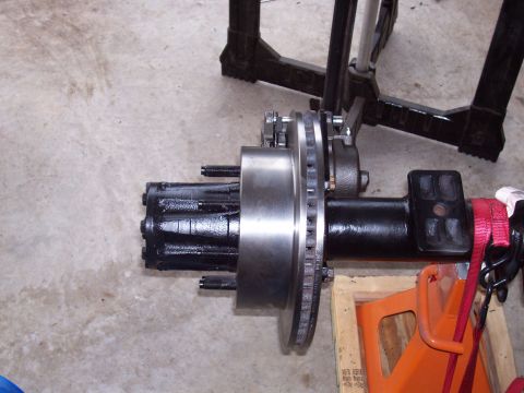 1994 Ford Bronco - Close-up of a vehicle axle assembly, showing the brake rotor and hub components, resting on jack stands.