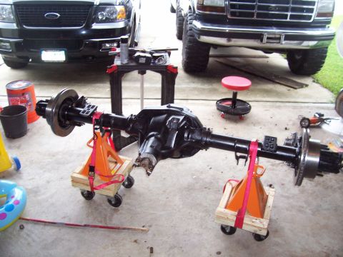 1994 Ford Bronco - A rear axle assembly is prepared for installation, with two Ford trucks visible in the background.