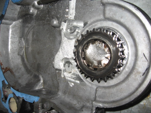 Opened aluminum transmission case showing splined shaft and gear with weld repairs on the housing
