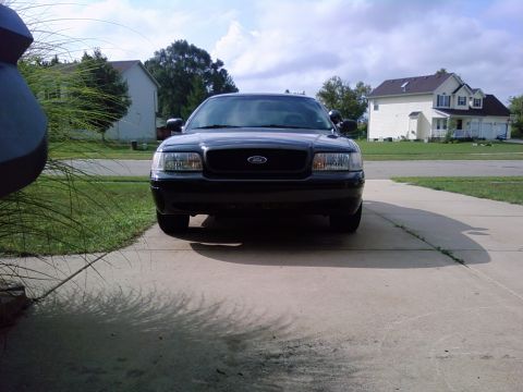 2003 Ford Crown Victoria - A black 2003 Ford Crown Victoria is parked in a suburban driveway on a cloudy day.