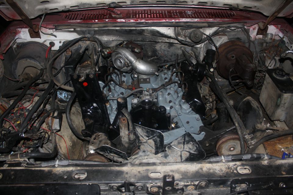 Engine bay with a turbocharger installed on the engine. Lots of wiring and hoses visible
