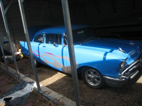 1957 Chevrolet Bel Air - A blue 1957 Chevrolet Bel Air, custom flame decals, is parked under a carport.