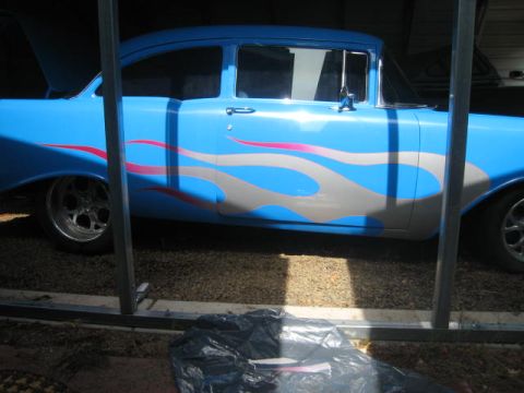 1957 Chevrolet Bel Air - Side view of a blue 1957 Chevrolet Bel Air sedan custom flame graphics.