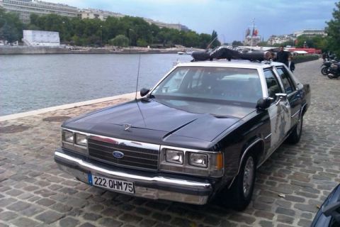 1991 Ford Crown Victoria - This 1991 Ford Crown Victoria police car is parked by a river with a cityscape in the background.