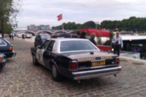 1991 Ford Crown Victoria - A 1991 Ford Crown Victoria police car is seen from the rear, parked on a cobblestone street near a body of water.