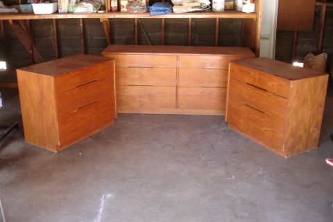 1993 Ford Taurus - Three wooden dressers are set up in a garage with shelving above.