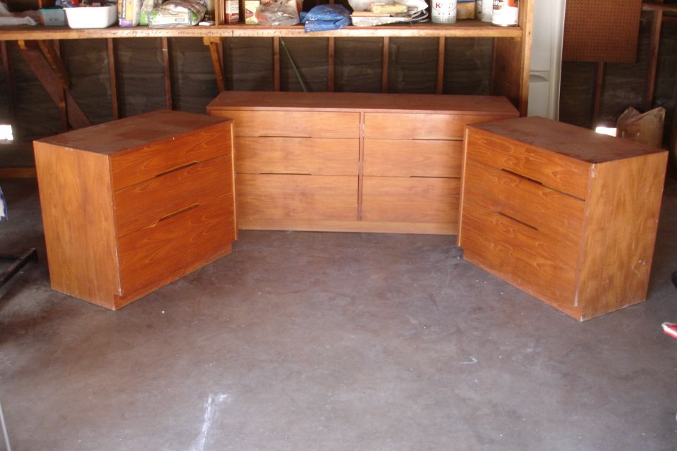 Three wooden dressers arranged in a garage setting