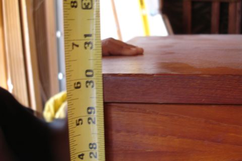 1993 Ford Taurus - A yellow measuring tape is placed next to a wooden surface, with a hand resting on the wood.