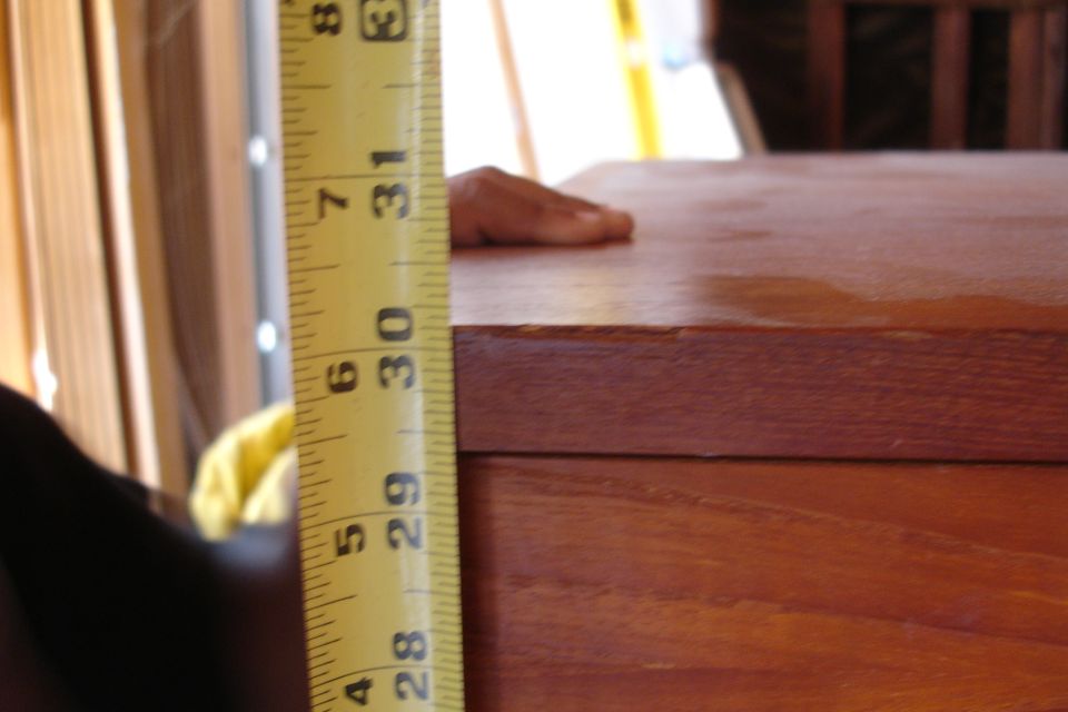 Yellow measuring tape showing inches next to a wooden surface