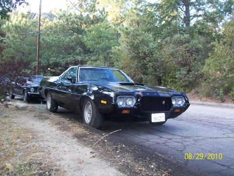 1972 Ford Ranchero - This black pickup truck, likely from the early 1970s, features a prominent hood scoop and quad headlights.